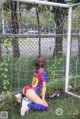 A woman sitting on the ground in front of a soccer goal.