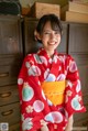 A woman in a red kimono smiles at the camera.