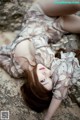 A woman laying on a rock in a dress.