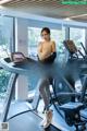 A woman is standing on a treadmill in a gym.