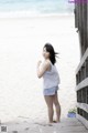 A woman standing on a wooden walkway next to the ocean.