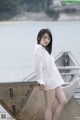 A woman in a white shirt standing next to a boat.