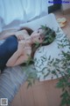 A woman laying on a bed next to a plant.