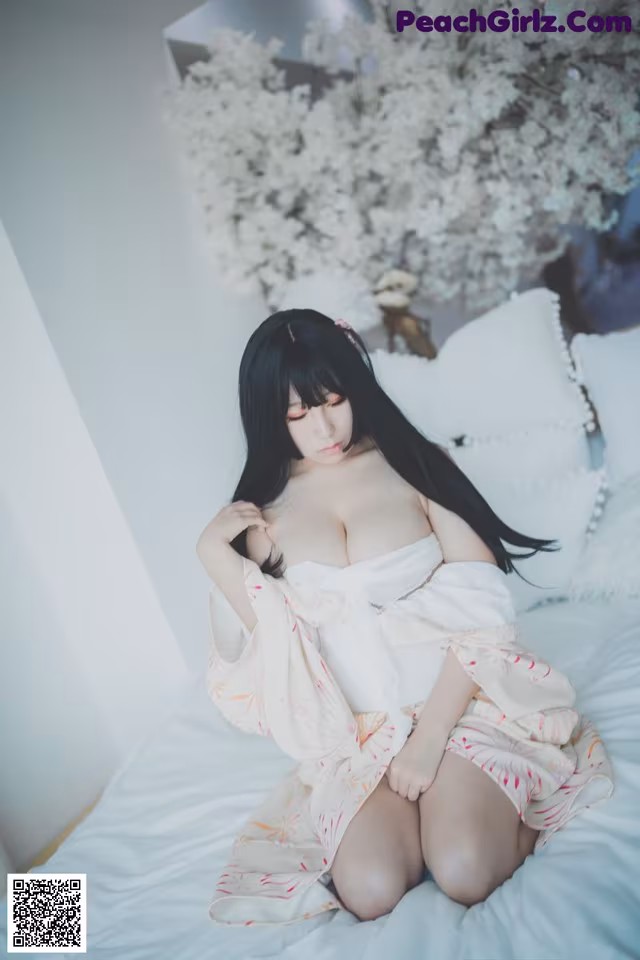 A woman sitting on a bed in a white dress.