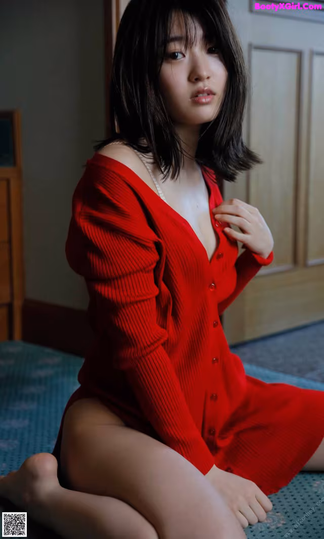 A woman in a red dress sitting on the floor.
