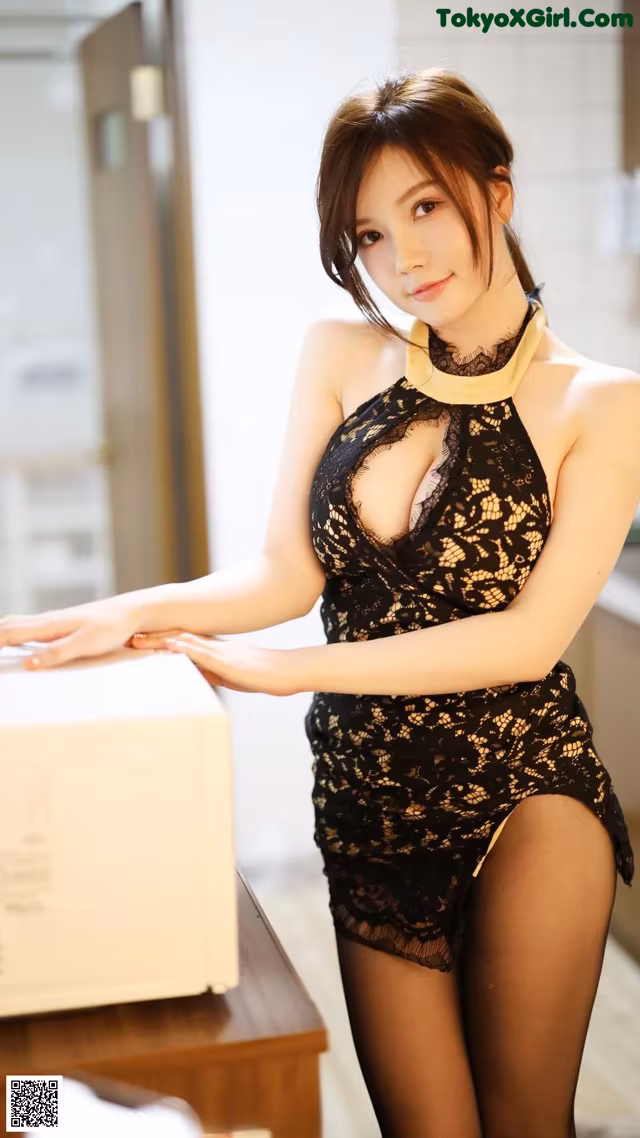 A woman in a black and gold lingerie posing for the camera.