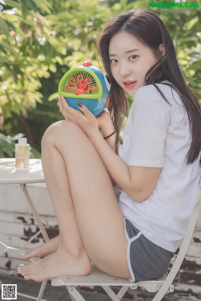 A woman sitting on a chair holding a watermelon.