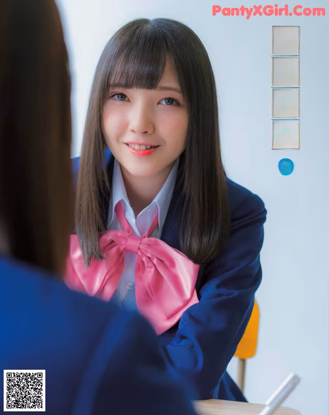 A young woman in a school uniform sitting at a desk.