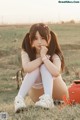 A young woman sitting on the ground in a field.