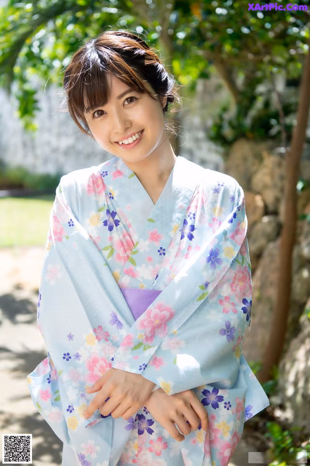A woman in a blue and pink kimono posing for a picture.