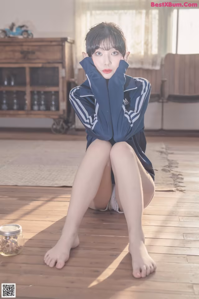 A woman sitting on the floor with her legs crossed.