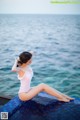 A woman in a white bathing suit sitting on the edge of a swimming pool.