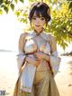 A woman in a kimono standing on a beach next to a tree.