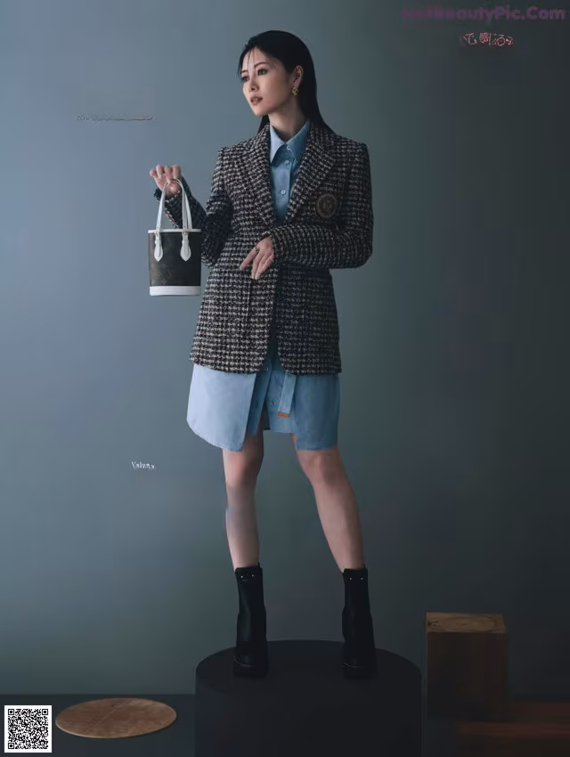 A woman standing on top of a pedestal holding a handbag.