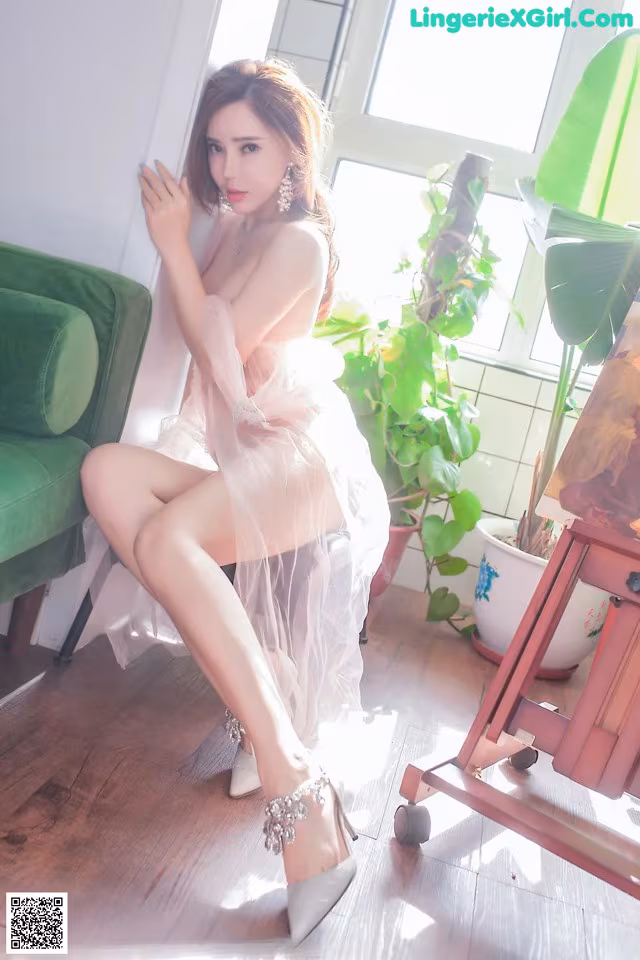 A woman in a white dress sitting on a green couch.
