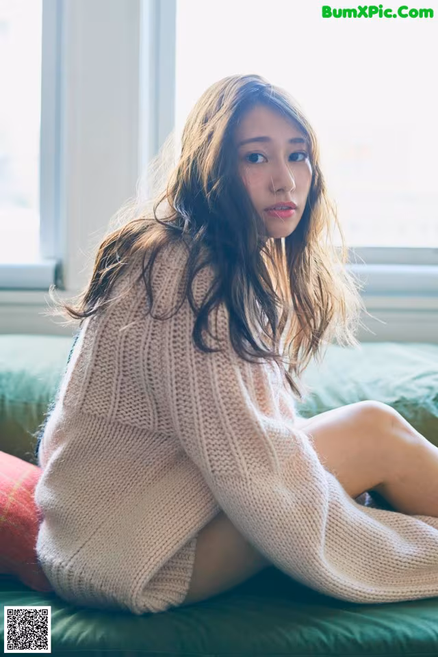 A woman sitting on top of a green couch.