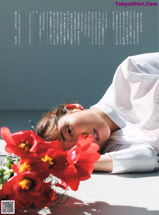 A woman laying on the ground next to a bunch of flowers.