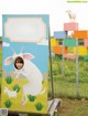 A woman standing in front of a sign with a goat on it.