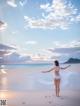 A woman in a white bikini standing on a beach.