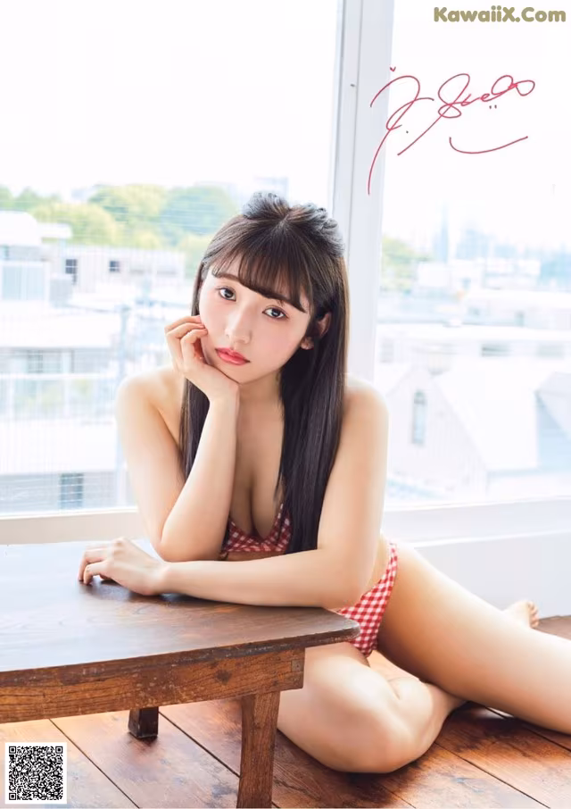 A woman in a red and white bikini sitting on a wooden table.